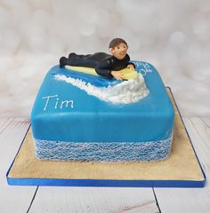 a birthday cake with a man laying on a surfboard in the middle of it