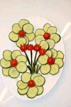 cucumbers and tomatoes arranged on a white plate with red cherry tomatoes in the center