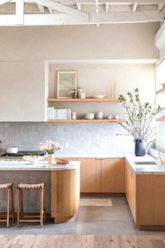 an open kitchen with wooden cabinets and counter tops, along with two stools in front of the island