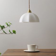 a coffee cup sitting on top of a wooden table next to a white light fixture