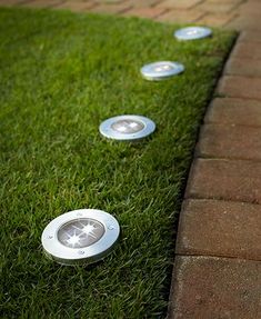 several lights are placed in the grass near a brick path