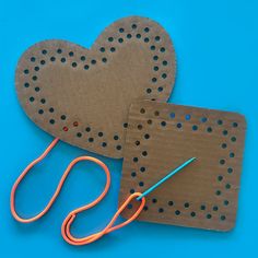 two pieces of cardboard with scissors next to each other on a blue background and one piece has holes in the shape of a heart