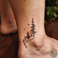 a small pine tree tattoo on the side of a foot with dots and stars in it