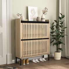 a wooden cabinet sitting next to a potted plant and white shoes on the floor