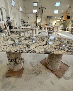 a marble table in a large room with several tables and stools on the floor