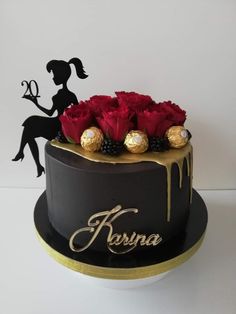 a black cake with red roses and chocolates on the top is decorated with gold lettering