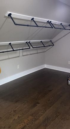 an empty room with some clothes hanging from the ceiling and two shoes on the floor