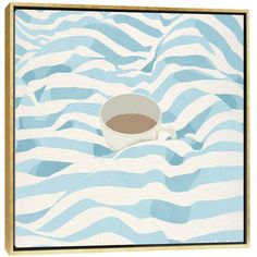 a cup of coffee sitting on top of a blue and white striped table cloth with waves