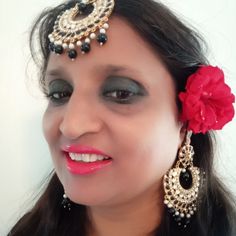 a woman with black makeup and red flower in her hair