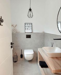 a white toilet sitting next to a bathroom sink under a light hanging from the ceiling