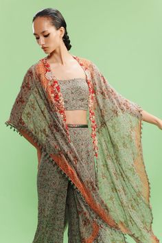 Green and burnt orange batwing sleeves long front open cape with all over ditsy flora print and hand embroidered borders. Paired with a matching print and embellished square neckline bustier and a printed sharara. - Aza Fashions Cape Sharara, Dolly J, Printed Sharara, Embroidered Bustier, Drape Sarees, Embroidered Belt, Cocktail Gowns, Open Neck, Sharara Set