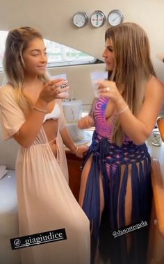 two beautiful young women standing next to each other in front of a bathroom sink and mirror