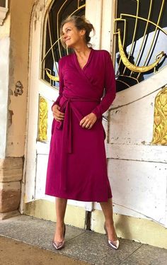 a woman standing in front of a door wearing a purple dress