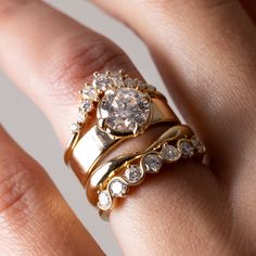 a woman's hand with two gold rings on top of her finger and the other ring