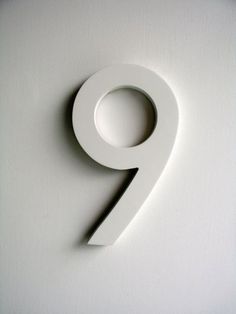 the number nine is made up of white paper and placed on top of a wall