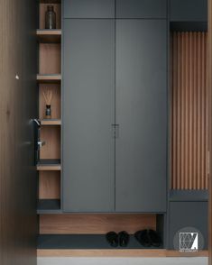 an empty closet with shoes on the floor and wooden shelves above it, in front of a wall mounted cabinet