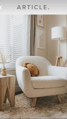 a teddy bear sitting in a white chair next to a window with blinds on it