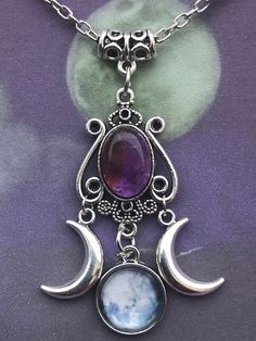 A stunning piece of Jewellery for any occasion . A filigree bail holds this beautiful triple moon Amethyst pendant . Consisting of a 1.5x1cm Oval Amethyst set in an ornate cabochon tray , suspended from the main pendant are two silver tone double sided crescent moons . The centre hanging pendant is a glass cabochon and tray featuring a stunning full moon. The total size of the pendant from Bail to moon cabochon is 6cm . The chain is 20inches .  I include a card ( the necklace will be presented on the card in clear film envelope. I include a purple organza bag . Bohemian Amethyst Moon Charm Jewelry, Mystical Amethyst Moon Phase Jewelry, Purple Bohemian Jewelry With Moon Charm, Bohemian Purple Jewelry With Moon Charm, Bohemian Amethyst Moon Phase Jewelry, Mystical Moon Phase Purple Jewelry, Spiritual Purple Necklace With Moon Charm, Mystical Purple Moon Phase Jewelry, Spiritual Amethyst Necklace With Moon Charm