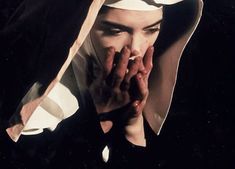 a nun holding her hands up to her face while wearing a black and white outfit