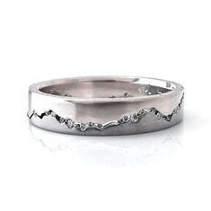 a white gold wedding ring with wavy lines on the side and diamond accents in the middle