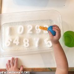 a young child is playing with numbers on a tray