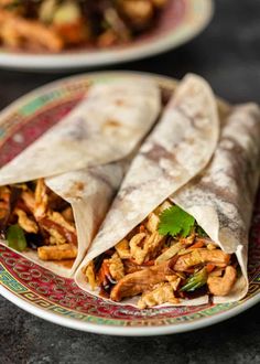 two burritos with chicken and vegetables on a plate