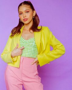 a woman in pink pants and a yellow jacket posing for the camera with her hands on her hips