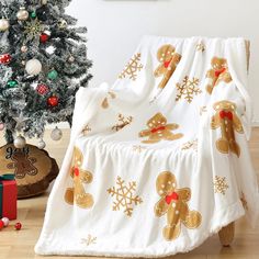 a white blanket with gingerbreads on it next to a christmas tree