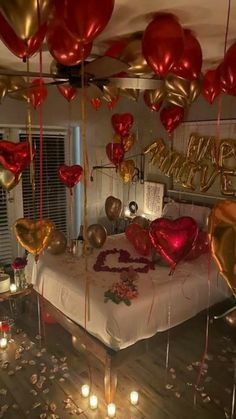 a bedroom decorated for valentine's day with balloons and candles