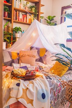 a bed with a canopy over it in a room filled with plants and bookshelves