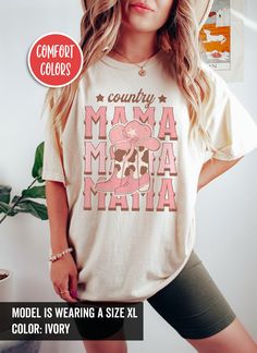 Embrace your inner cowgirl with a touch of coquette charm in our "Country Mama" T-Shirt. It is perfect for rodeo enthusiasts who love to stand out. Whether you're at a rodeo, out on the town, or just showing off your playful side, this shirt adds a chic and unique touch to any outfit. Available on tshirt, sweatshirt, hoodies, tote bags and mugs: https://www.etsy.com/shop/TheNims?search_query=Country+Mama For other western themed items, click here: https://www.etsy.com/shop/TheNims?search_query=W White Short Sleeve Tops For Country Events, White Cotton Top For Country Events, White Cotton Tops For Country Events, Country Style Cotton Tops With Letter Print, Casual White Tops For Country Events, White Tops For Country Events In Summer, Country Style Tops For Spring Country Concerts, Relaxed Fit Tops For Country Concerts, Fall Cow Print Cotton Tops