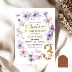 a floral birthday party card with purple flowers and gold foil lettering on the front, along with a pine cone