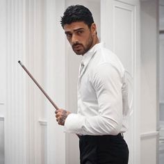 a man in a white shirt and black pants holding a stick with his right hand