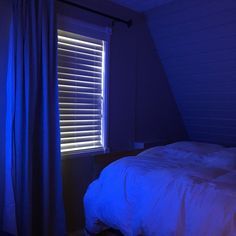 a bed sitting under a window next to a blue light