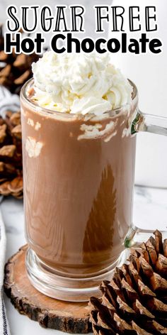 a hot chocolate drink with whipped cream in a glass mug and pine cones on the side