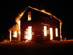 a house on fire in the dark with bright lights coming out of it's windows