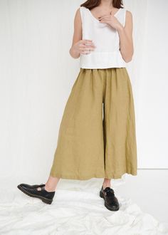 "The Clementine palazzo is the right choice for warmer days when you want to give a romantic touch to your look. The pants boast a cropped hem, in-seam pockets and a flattering gathered skirt-like high waist with an elastic band in the back. IMPORTANT: The Clementine pants have been altered to have a gathered waist instead of the pleated one. If you own a pair with pleated front, note that the pants you will receive will be different. This garment is true to size, and we recommend choosing the s Olive Wide Leg Relaxed Fit Pants, Chic Olive Summer Pants, Olive Bottoms With Elastic Waistband For Spring, Olive Wide Leg Pants For Spring, Olive Wide Leg Pants With Elastic Waistband, Olive Wide-leg Spring Pants, Olive Wide-leg Pants For Spring, Chic Olive Pants For Spring, Olive Relaxed Fit Pants For Summer