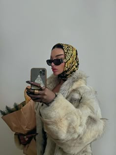 a woman in a fur coat holding a cell phone