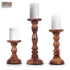 three wooden candlesticks with white candles in them on a white background and the words luxe designs written below