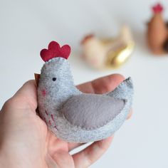 a hand holding a small gray and red bird