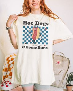 a woman holding up a hot dog t - shirt with the words hot dogs and home runs on it