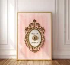 a pink wall with a gold frame and a white toilet paper dispenser