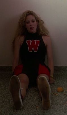 a young woman sitting on the floor with her legs crossed and mouth wide open, wearing a black shirt that says w