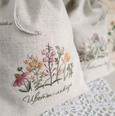 two embroidered bags sitting on top of a white doily next to a lace table cloth