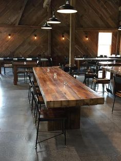 a large wooden table sitting inside of a restaurant next to two tables with chairs around it