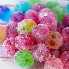 there are many different colored candies on the table with water droplets all over them