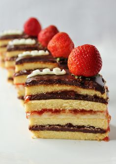 several slices of cake with chocolate and strawberries on top