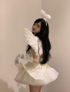 a woman dressed in white is posing for the camera with her wings spread out and she has long black hair