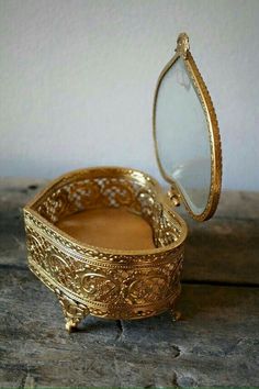 an ornate gold jewelry box sitting on top of a wooden table