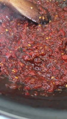 a wooden spoon stirring red sauce in a slow cooker